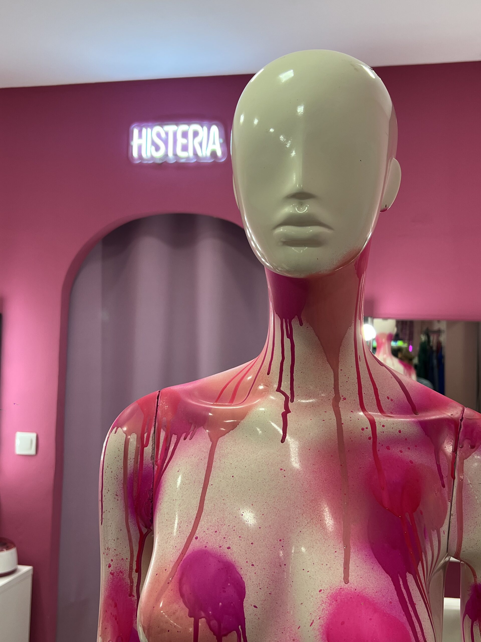 Maniquí de la tienda con decoración artística Primer plano de un maniquí blanco con pintura rosa goteando y el letrero 'HISTERIA